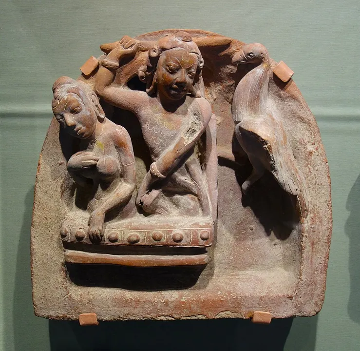 An old terracotta plaque of two figures seated close together, with a large bird perched beside them.