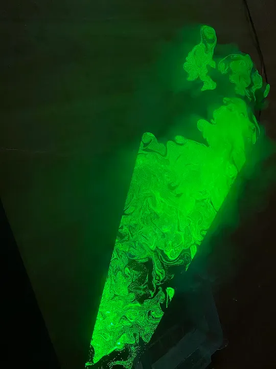 A bright green beam of light glowing through swirling smoke in a dark room.