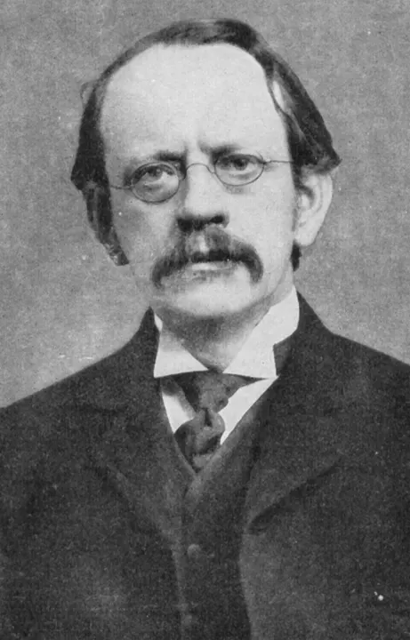 A black-and-white portrait of a man with glasses and a moustache.
