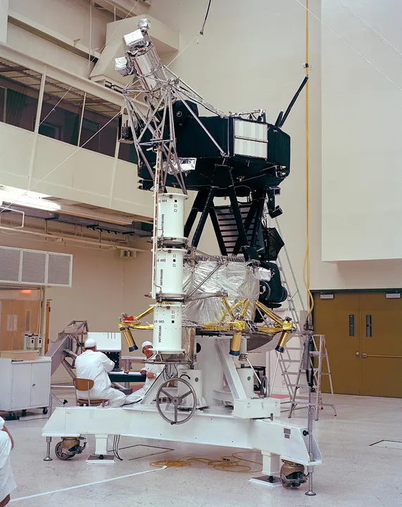 A spacecraft with a large white dish antenna and a long boom.