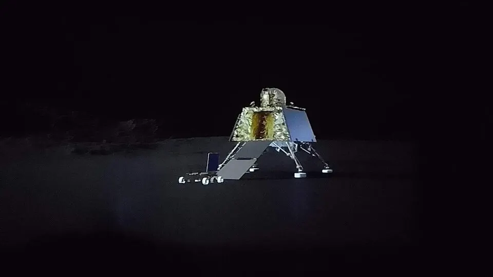 A gold-foil lunar lander resting on grey ground, a computer render.