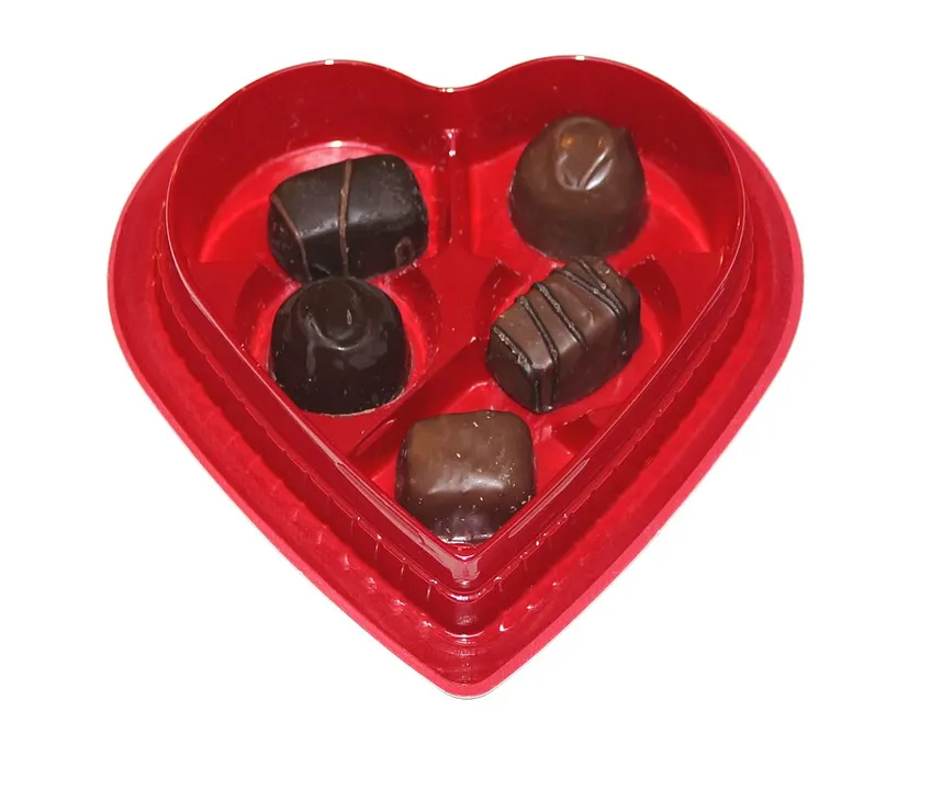 A red heart-shaped tray holding five different chocolates.