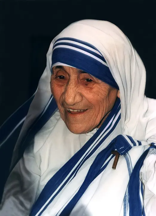 An elderly woman in a white sari with blue borders.