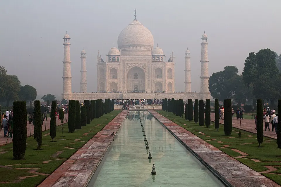 A white marble mausoleum with four minarets beside a long reflecting pool.