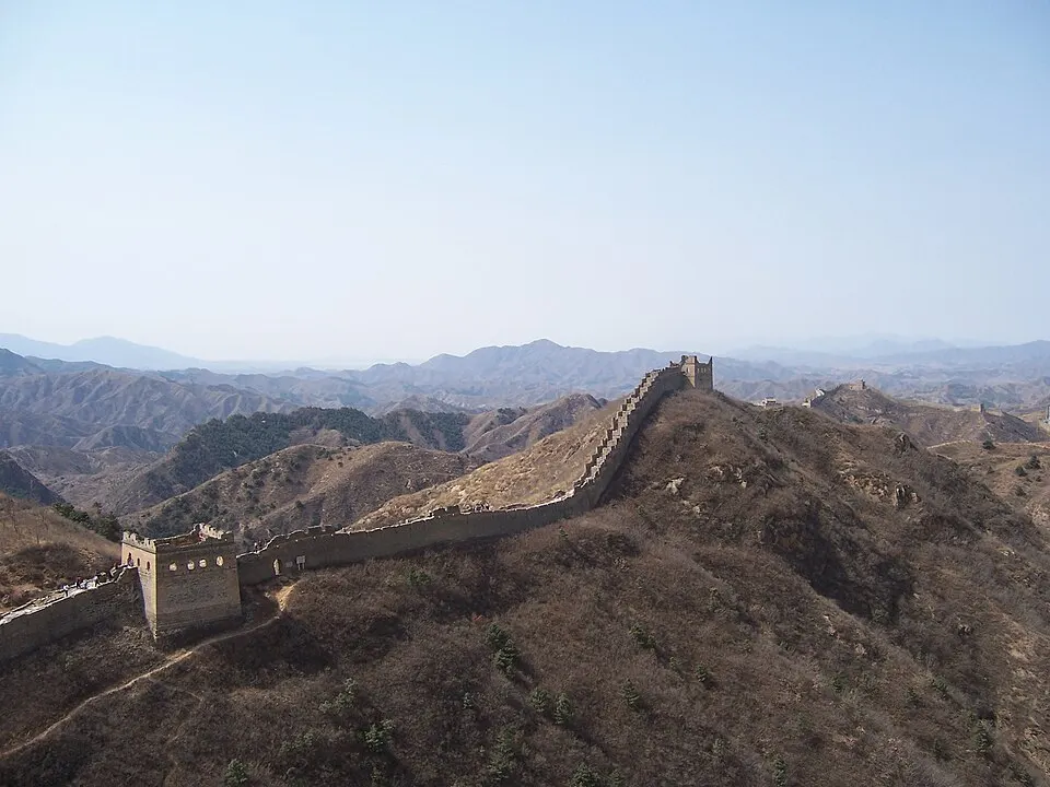 A stone wall with watchtowers snaking over green mountain ridges.