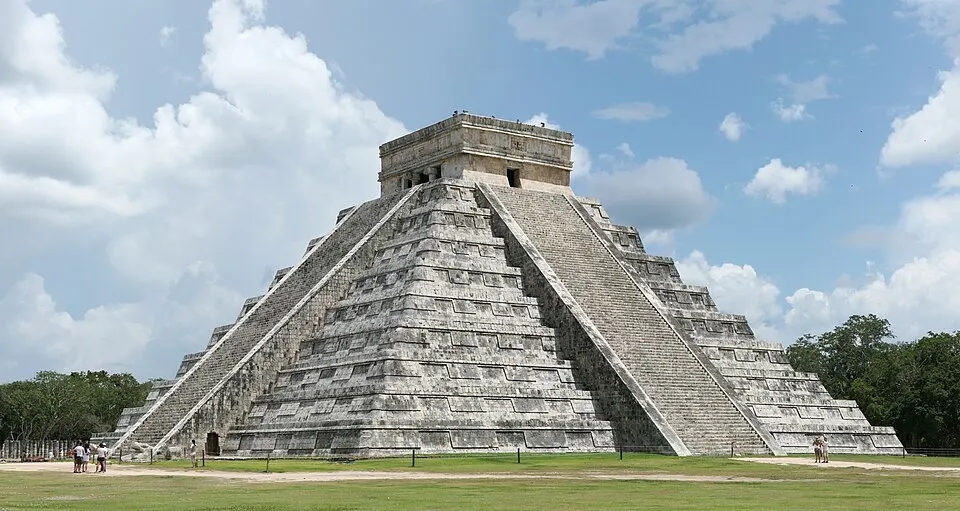 A stepped stone pyramid with a staircase up each side, in a clearing.