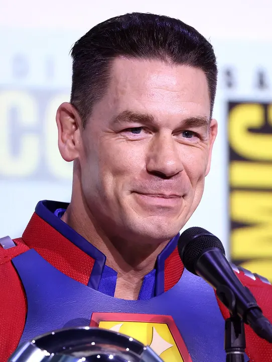 A smiling man in a superhero T-shirt at a fan convention.