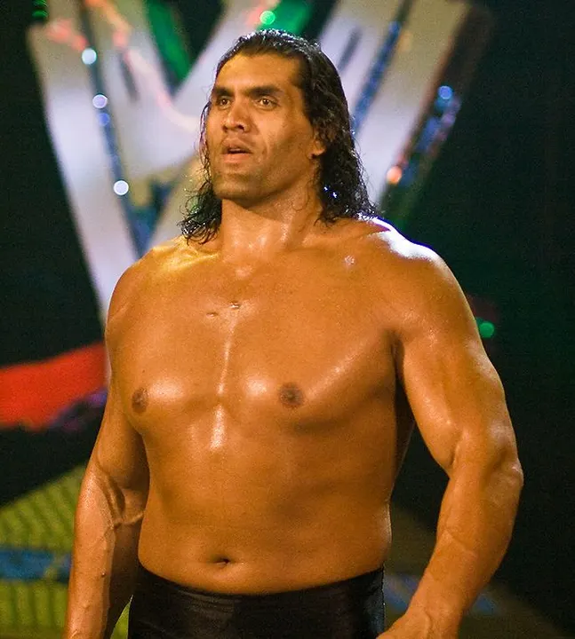 An extremely tall, muscular wrestler standing shirtless.